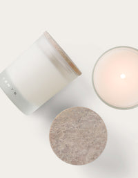 One lit candle, one candle laying on its side, one stone candle lid